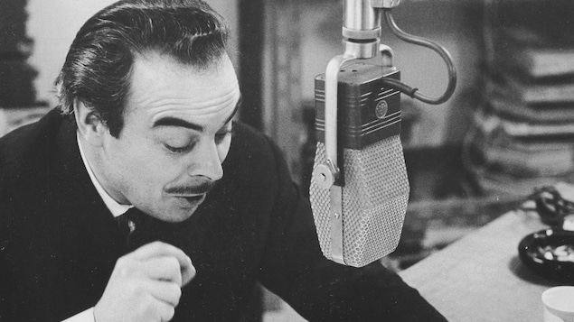 Henri Bergeron lit un conte dans un studio radio avec un visage particulièrement expressif.