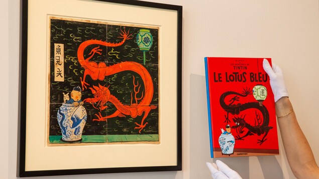Le dessin où l'on voit Tintin dans un grand vase chinois avec Milou, faisant face à un grand dragon rouge, est encadré et affiché sur un mur. À droite, des mains tiennent une copie de la version imprimée de la couverture du « Lotus bleu ».