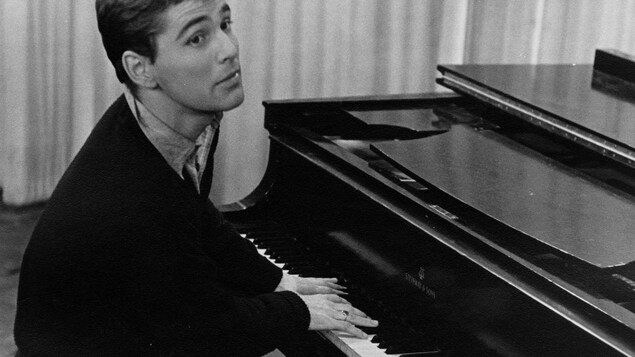 Dans un studio de télévision, le chanteur québécois Hervé Brousseau est assis à un piano, les mains sur le clavier. Dans un studio de télévision, le chanteur québécois Hervé Brousseau est assis à un piano, les mains sur le clavier.
