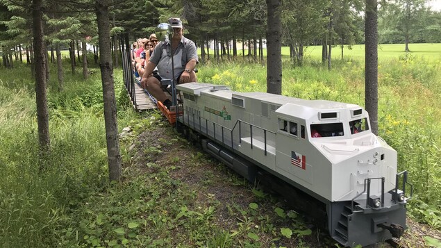 Un train en miniature transportant des personnes. 