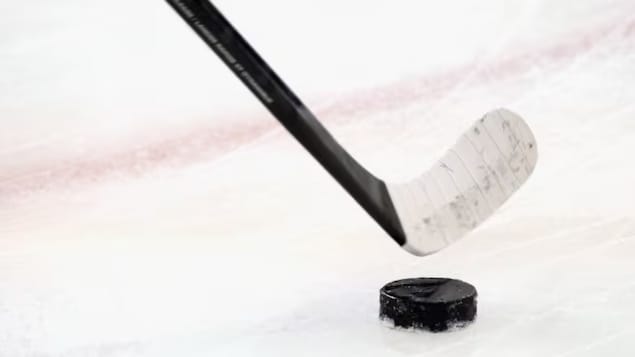 Un bâton de hockey devant une rondelle.