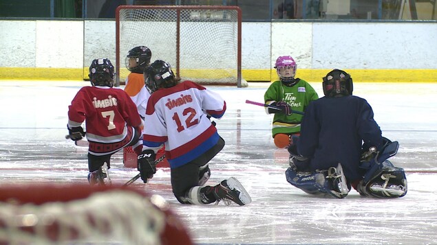 De jeunes joueurs de hockey s'exercent sur une patinoire.