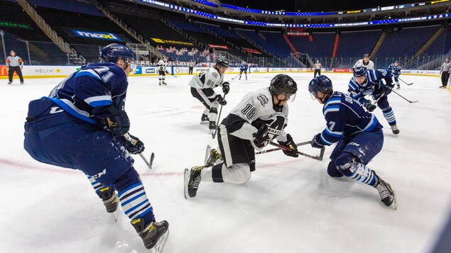Des joueurs de hockey dans un aréna vide.