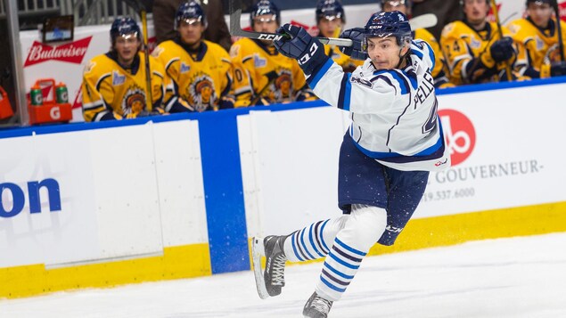 Un joueur de hockey fait un lancer frappé.