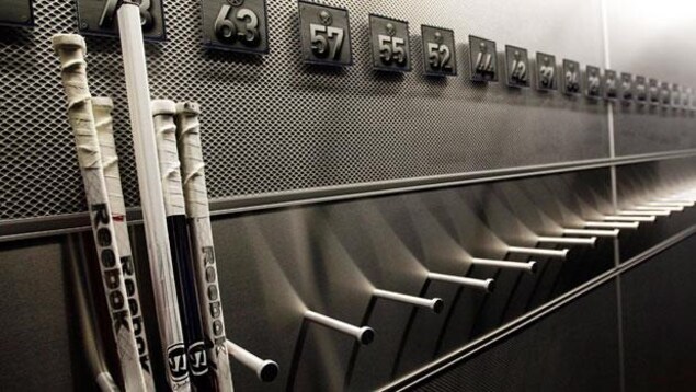 Des bâtons de hockey dans un vestiaire.