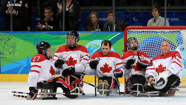 Des joueurs de hockey sur luge. Derrière, le premier ministre canadien de l'époque, Stephen Harper. Des joueurs de hockey sur luge. Derrière, le premier ministre canadien de l'époque, Stephen Harper.