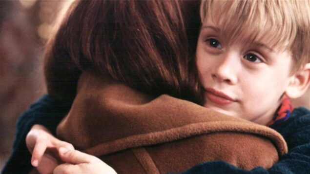 L'enfant est dans les bras d'une adulte.