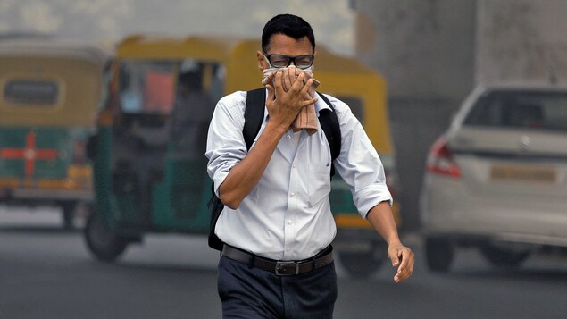 Un homme se couvre le visage dans les rues de New Delhi.