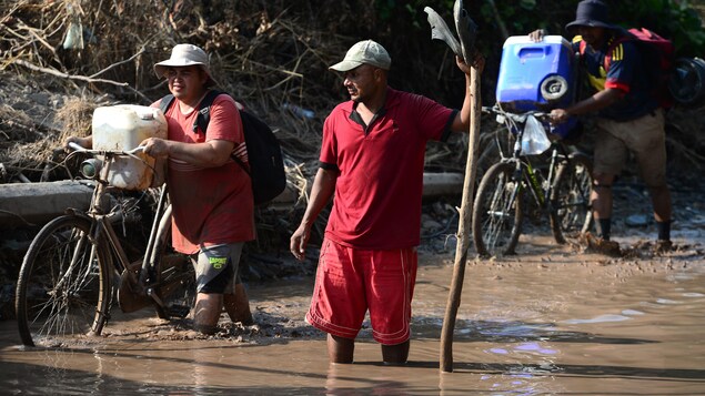 Des travailleurs dans la boue avec leurs vélos au Honduras.