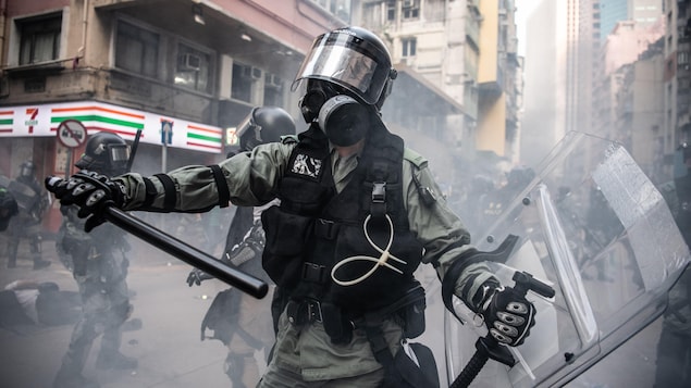 Un policier avec un bâton, et portant des protections
