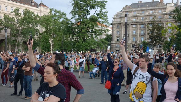 Des manifestants tiennent en l'air leurs téléphones en mode flashlight.