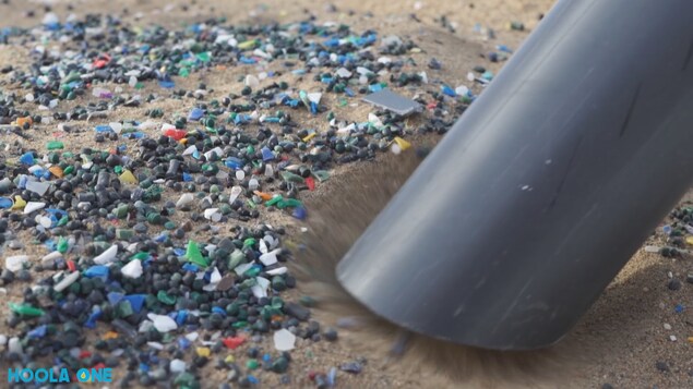 Un appareil aspire des morceaux de plastique sur la plage.