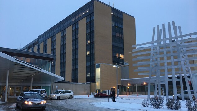 Jouxtant l’hôpital, beige et noir, la chaussée est enneigée. Jouxtant l’hôpital, beige et noir, la chaussée est enneigée.