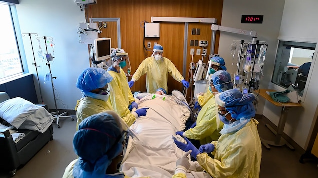 Sept médecins entourent un patient dans une chambre d'hôpital.