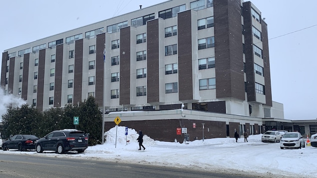 Des piétons marchent dans la neige devant l'Hôpital de Rouyn-Noranda.