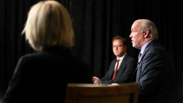 Le premier ministre de la Colombie-Britannique, John Horgan, en compagnie du ministre de la Santé, Adrian Dix, et de la médecin hygiéniste en chef, Bonnie Henry.
