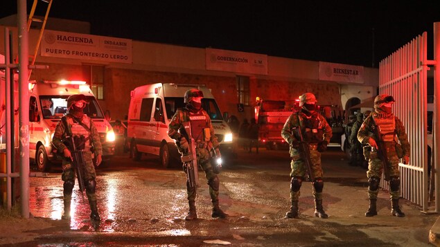 Des soldats se tiennent debout devant des ambulances à l'extérieur d'un centre de détention.