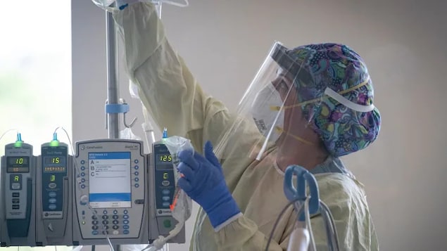 Une employée des services médicaux portant un masque N95 et une visière au travail dans un hôpital albertain.