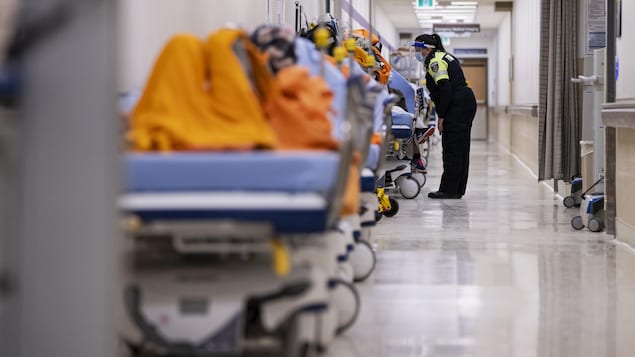 Une ambulancière fait la tournée des patients sur des civières aux urgences de l'hôpital Humber River de Toronto