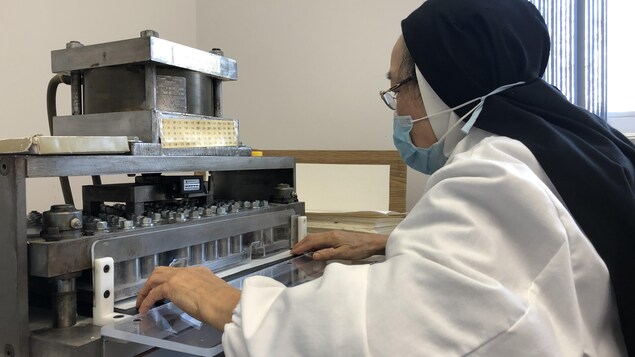 Une religieuse opère une machine destinée à la production d'hosties.
