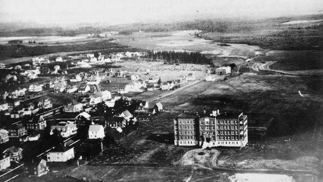 Une photo aérienne d'archive de la ville de Moncton en noir et blanc. Très rural, il y a quelques maisons et une immense hôpital. 
