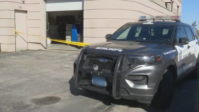 Un voiture de police devant la porte arrière barrée d'un hôtel.