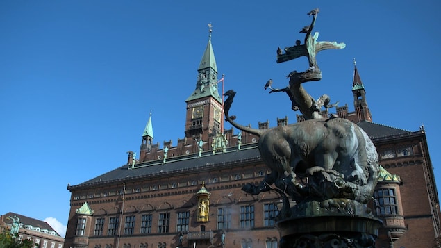 On voit la façade de l'hôtel de ville de Copenhague, avec, en avant-plan, une statue de bronze. On voit la façade de l'hôtel de ville de Copenhague, avec, en avant-plan, une statue de bronze.