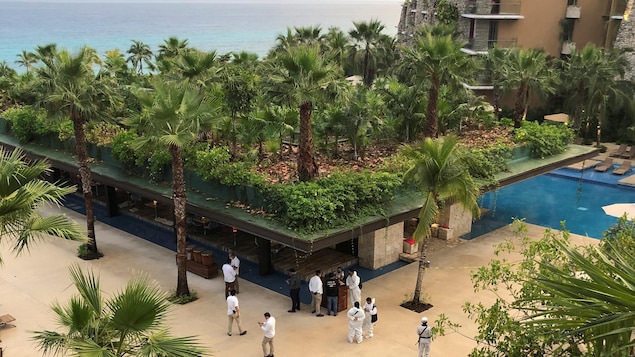 Forensic technicians and hotel employees stand near a scene where two Canadians were killed and a third wounded in a shooting at Hotel Xcaret in Mexico's Quintana Roo state on Friday.