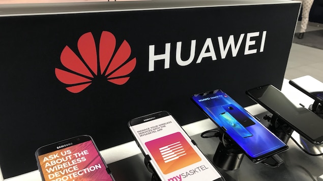 Des téléphones cellulaires vendus par SaskTel devant un présentoir portant le logo de Huawei.