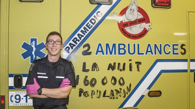 Un homme debout devant une ambulance de couleur jaune.