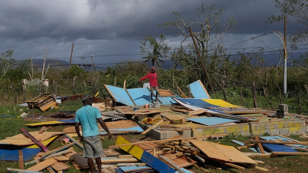 Residents stand on the wreckage of a house destroyed by Hurricane Melissa in Santa Cruz, Jamaica, on Oct. 29. For the past decade, Jamaica has been building layers of financial protection in the event of a natural disaster. Now, after Hurricane Melissa tore through the country, destroying homes, roads and essential infrastructure, the country's strategy might pay off — and provide a model for climate-vulnerable nations elsewhere. 
