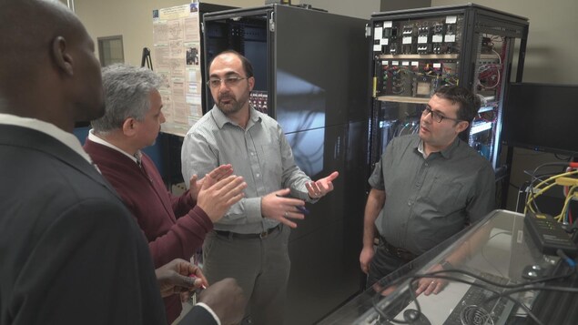 Quatre hommes se parlent dans une salle d'informatique. Quatre hommes se parlent dans une salle d'informatique.