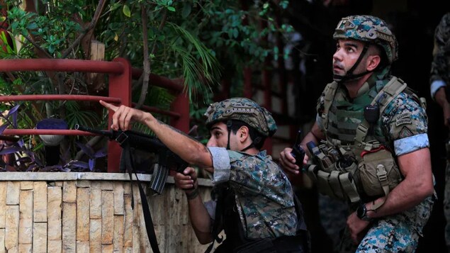 Lebanese security forces react to gunfire during a protest in Beirut, Lebanon, on Thursday. Armed clashes broke out in Beirut during a protest against the lead judge investigating last year’s massive blast in the city's port as tensions over the domestic probe boiled over. (Hussein Malla/The Associated Press)
