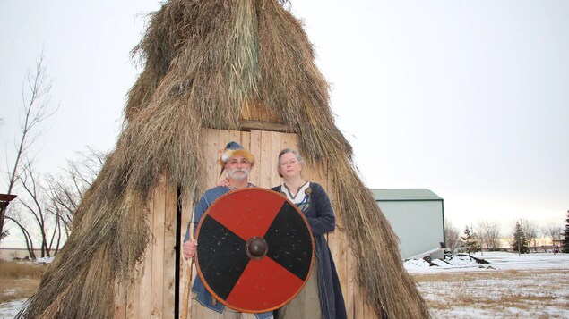 Wendy Speary et Pedro Bedard devant leur hutte avec des vêtements et accessoires du temps des Vikings.