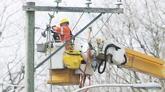 Un employé d'Hydro-Québec travaille sur un pylône électrique.