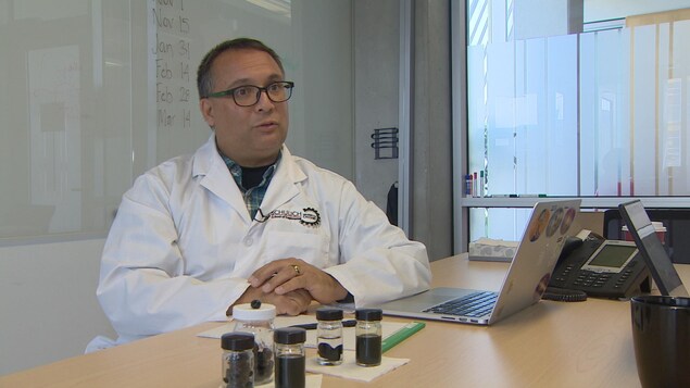 Devant Ian Gates, il y a cinq flacons, dont trois contiennent des billes de pétrole solide. Devant Ian Gates, il y a cinq flacons, dont trois contiennent des billes de pétrole solide.