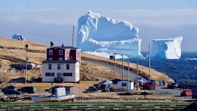 Des voitures immobiles sur la route côtière avec un iceberg en arrière-plan.