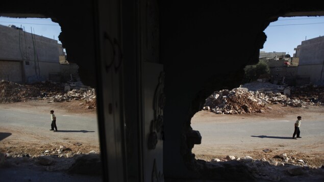 Un jeune Syrien marche à côté des décombres d'une maison détruite lors d'une opération militaire menée par l'armée syrienne en avril 2012, dans la ville de Taftanaz, à 15 km à l'est d’Idlib. Un jeune Syrien marche à côté des décombres d'une maison détruite lors d'une opération militaire menée par l'armée syrienne en avril 2012, dans la ville de Taftanaz, à 15 km à l'est d’Idlib.