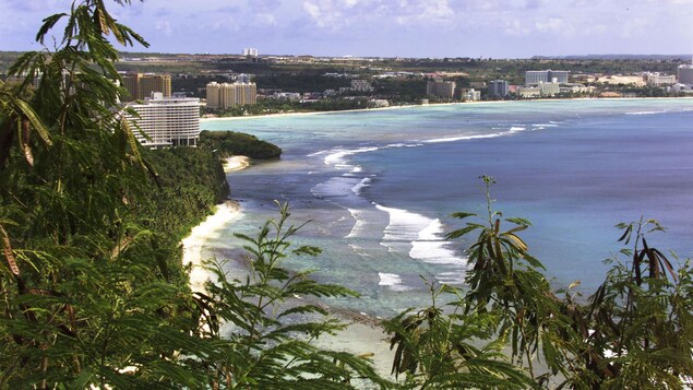 Vue en hauteur d'une plage de l'île de Guam et d'immeubles le long de la côte.