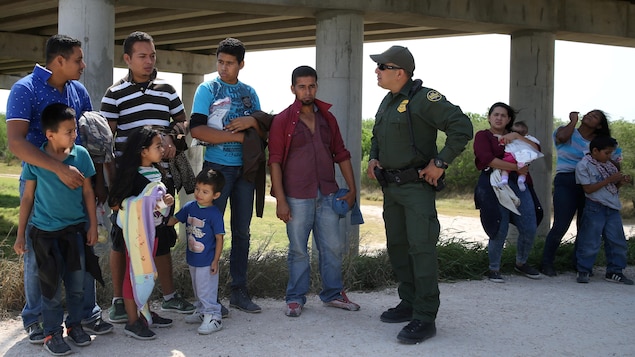 Un agent américain des services frontaliers discute avec des immigrants mexicains (adultes et enfants) qui ont traversé la frontière américaine illégalement, au Texas. Cette photo a été prise le 2 avril 2018.