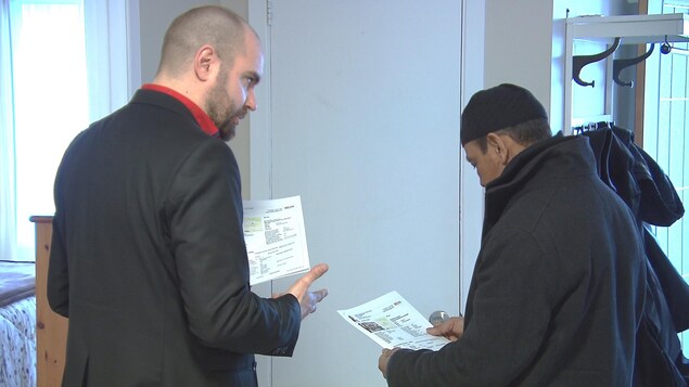 L'agent immobilier et le visiteur regardent sur une feuille de papier les spécifications de la maison à vendre. L'agent immobilier et le visiteur regardent sur une feuille de papier les spécifications de la maison à vendre.