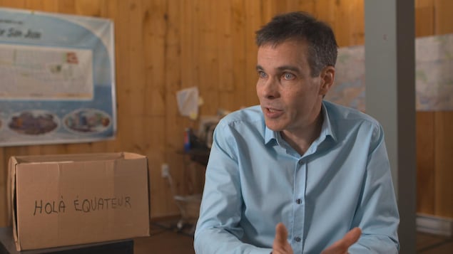 Yves Cormier en entrevue, un carton Hola Équateur en arrière-plan. Yves Cormier en entrevue, un carton Hola Équateur en arrière-plan.