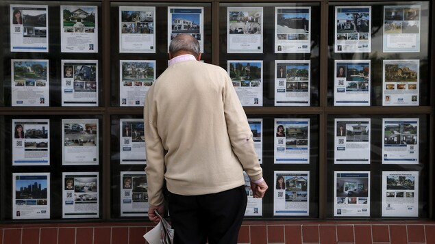 Une personne de dos regarde des maisons à vendre.