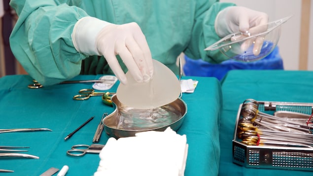 Une infirmière tient dans sa main un implant mammaire.