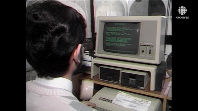 Un homme assis à un poste informatique avec un relevé T4 posé sur le clavier.