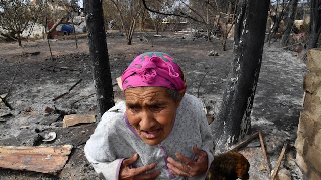 Une femme âgée devant sa maison détruite par l'incendie.