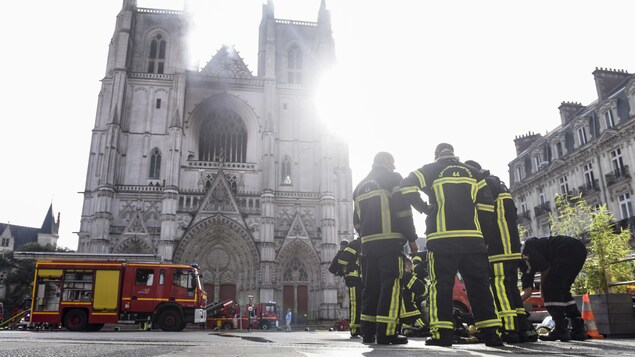 Des pompiers devant la cathédrale Saint-Pierre-et-Saint-Paul de Nantes endommagée par le feu.