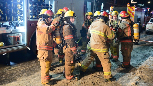Des pompiers en tenue dans la rue.