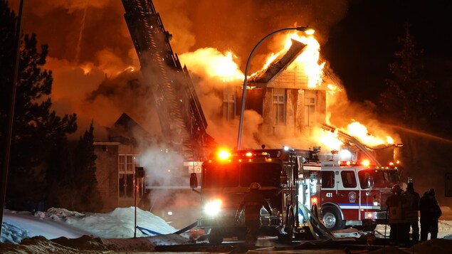 Des pompiers près d'un édifice en feu 