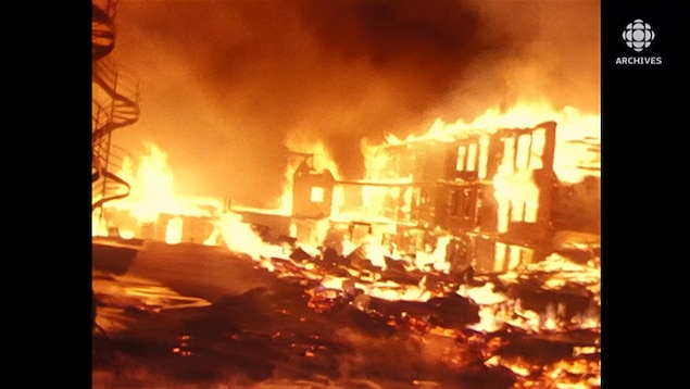 Immeuble en proie aux flammes avec des débris enflammés sur le sol.